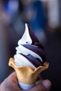 Close-up of creamy, swirled soft serve ice cream in a classic red and white vintage cone.