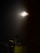 A glowing celestial body is surrounded by a soft halo against a dark night sky. Below it, the silhouette of a building with multiple antennas is visible, highlighting an urban rooftop scene. Tiny stars dot the background, adding to the tranquil ambiance.
