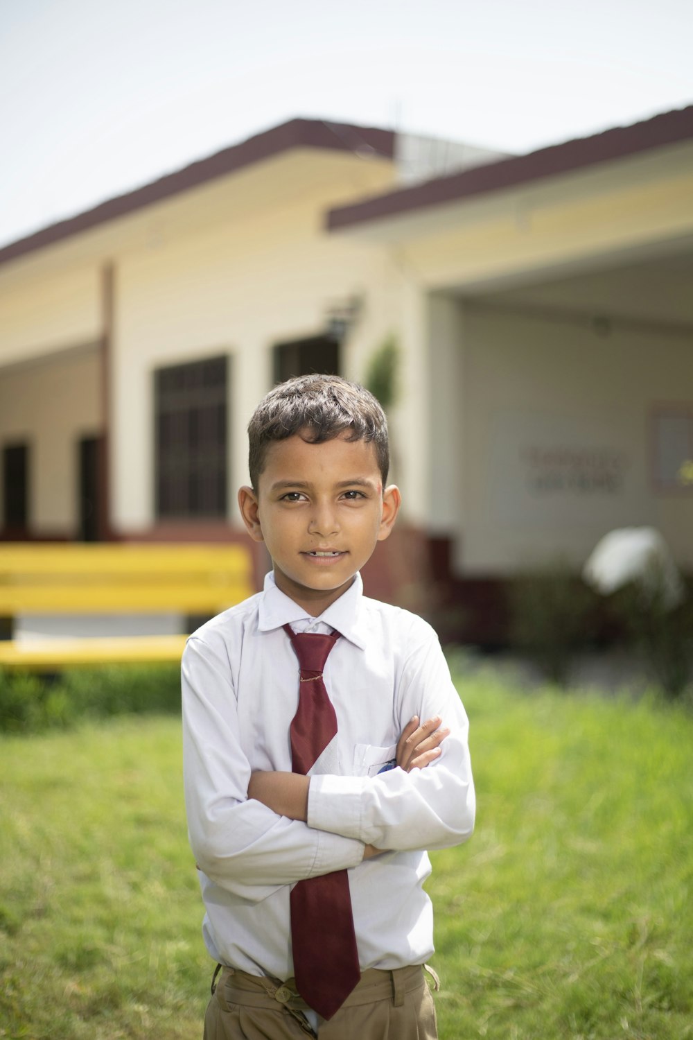 Ein kleiner Junge mit Krawatte steht vor einem Gebäude