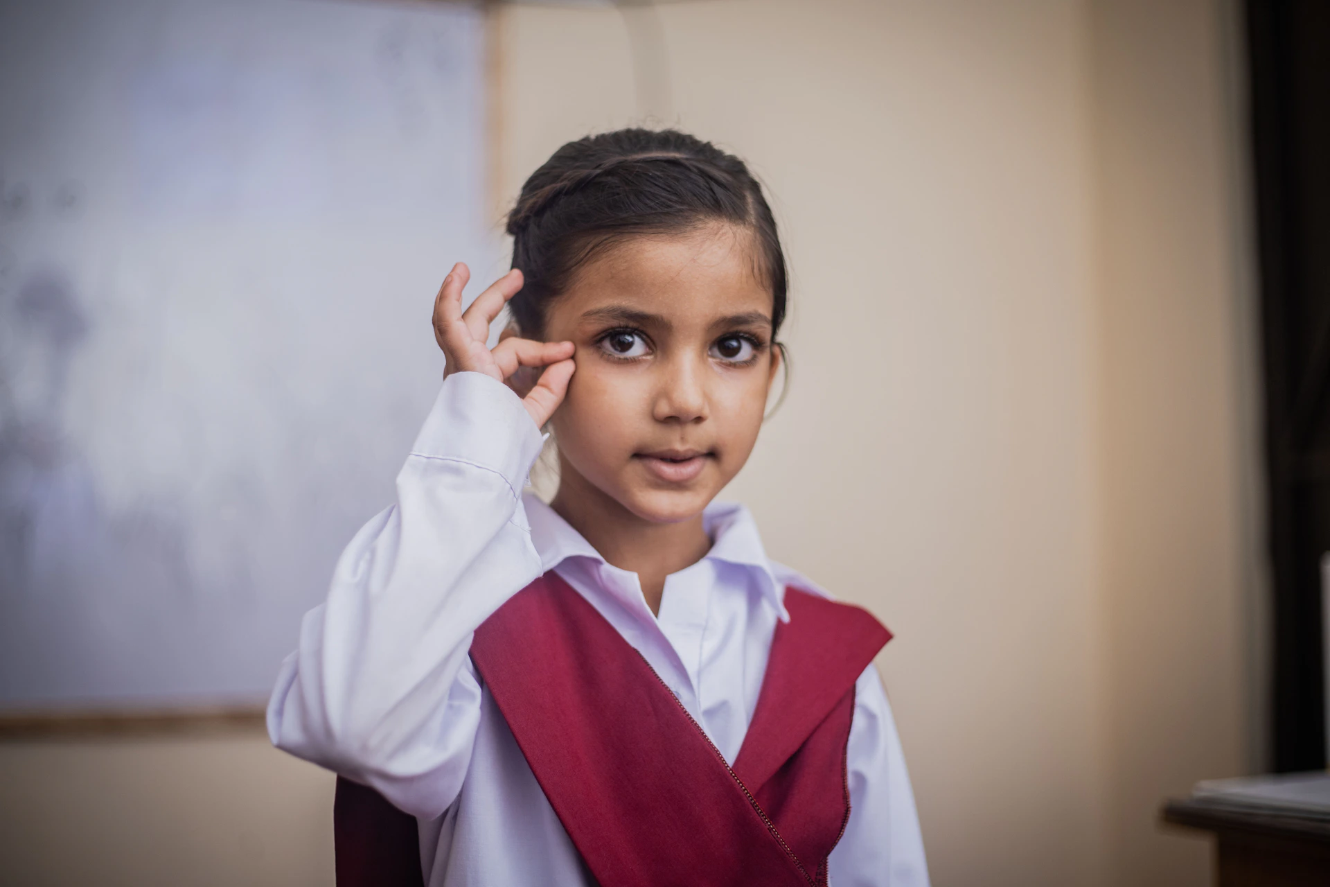a young girl wearing a red vest and white shirt
