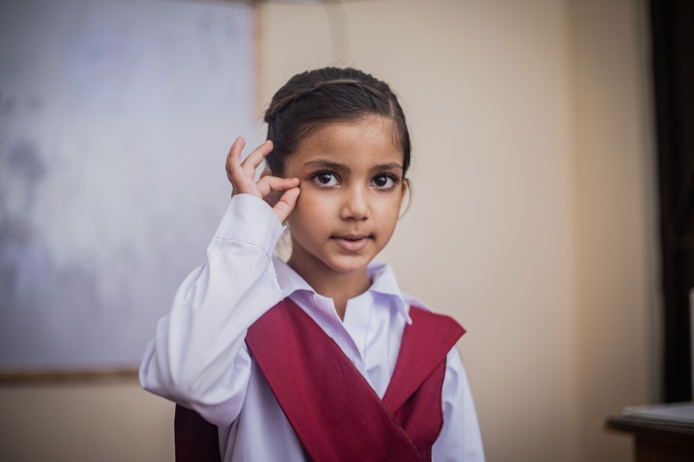 a young girl wearing a red vest and white shirt