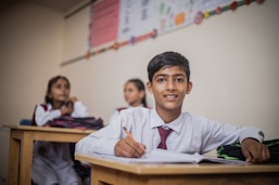 Close-up of a child’s hand holding a pencil, wearing a neat Wayki uniform sleeve.