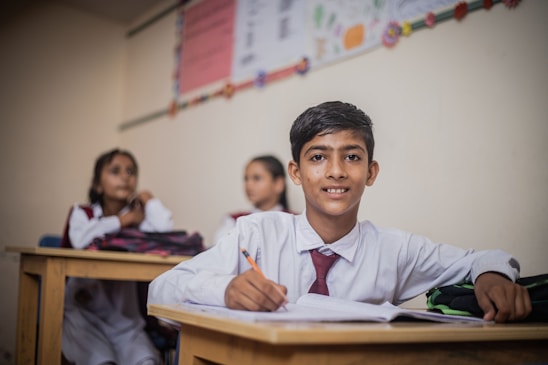 a young boy sitting at a desk in a classroom