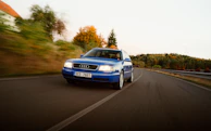 Driver enjoying the thrill behind the wheel of an Audi R8 on a coastal road.