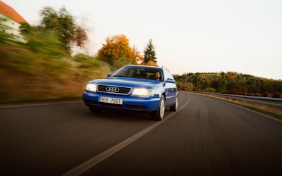 Glowing red Audi cruising along a coastal UK road with cliffs and ocean visible.