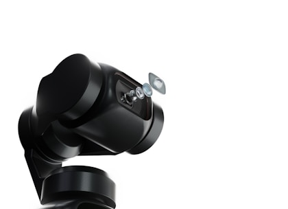 A robotic arm with a sleek, black design holds a series of lenses that appear to be suspended in mid-air. The background is a stark white, emphasizing the mechanical and sophisticated nature of the robotic technology.