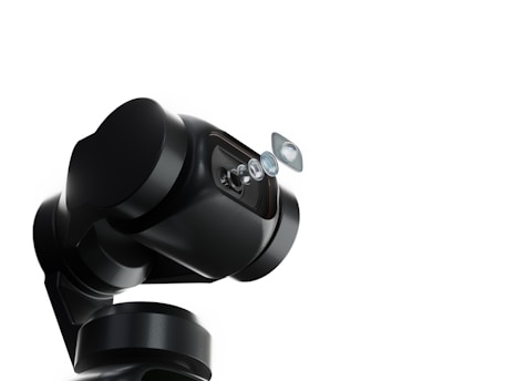 A robotic arm with a sleek, black design holds a series of lenses that appear to be suspended in mid-air. The background is a stark white, emphasizing the mechanical and sophisticated nature of the robotic technology.