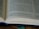 An open book with printed text, including a section of text and footnotes. The pages are light-colored and the text is in a dark font. The book is partially in focus, emphasizing the text at the center.
