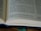 An open book with printed text, including a section of text and footnotes. The pages are light-colored and the text is in a dark font. The book is partially in focus, emphasizing the text at the center.