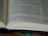 An open book with printed text, including a section of text and footnotes. The pages are light-colored and the text is in a dark font. The book is partially in focus, emphasizing the text at the center.