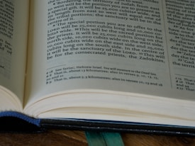 An open book with printed text, including a section of text and footnotes. The pages are light-colored and the text is in a dark font. The book is partially in focus, emphasizing the text at the center.