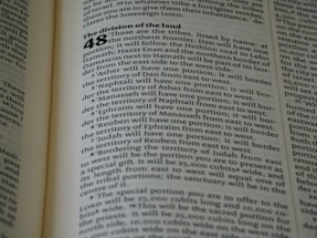 A close-up of an open book displaying a page with text. The layout is divided into sections with bold headings and numbered lists. The font is clear, and the lines of text are closely spaced. The lighting highlights the text, making it easy to read.