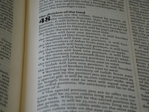 A close-up of an open book displaying a page with text. The layout is divided into sections with bold headings and numbered lists. The font is clear, and the lines of text are closely spaced. The lighting highlights the text, making it easy to read.