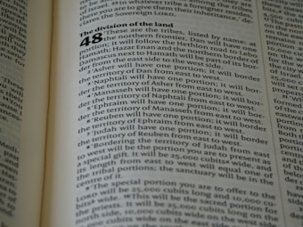 A close-up of an open book displaying a page with text. The layout is divided into sections with bold headings and numbered lists. The font is clear, and the lines of text are closely spaced. The lighting highlights the text, making it easy to read.