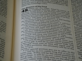 A close-up of an open book displaying a page with text. The layout is divided into sections with bold headings and numbered lists. The font is clear, and the lines of text are closely spaced. The lighting highlights the text, making it easy to read.