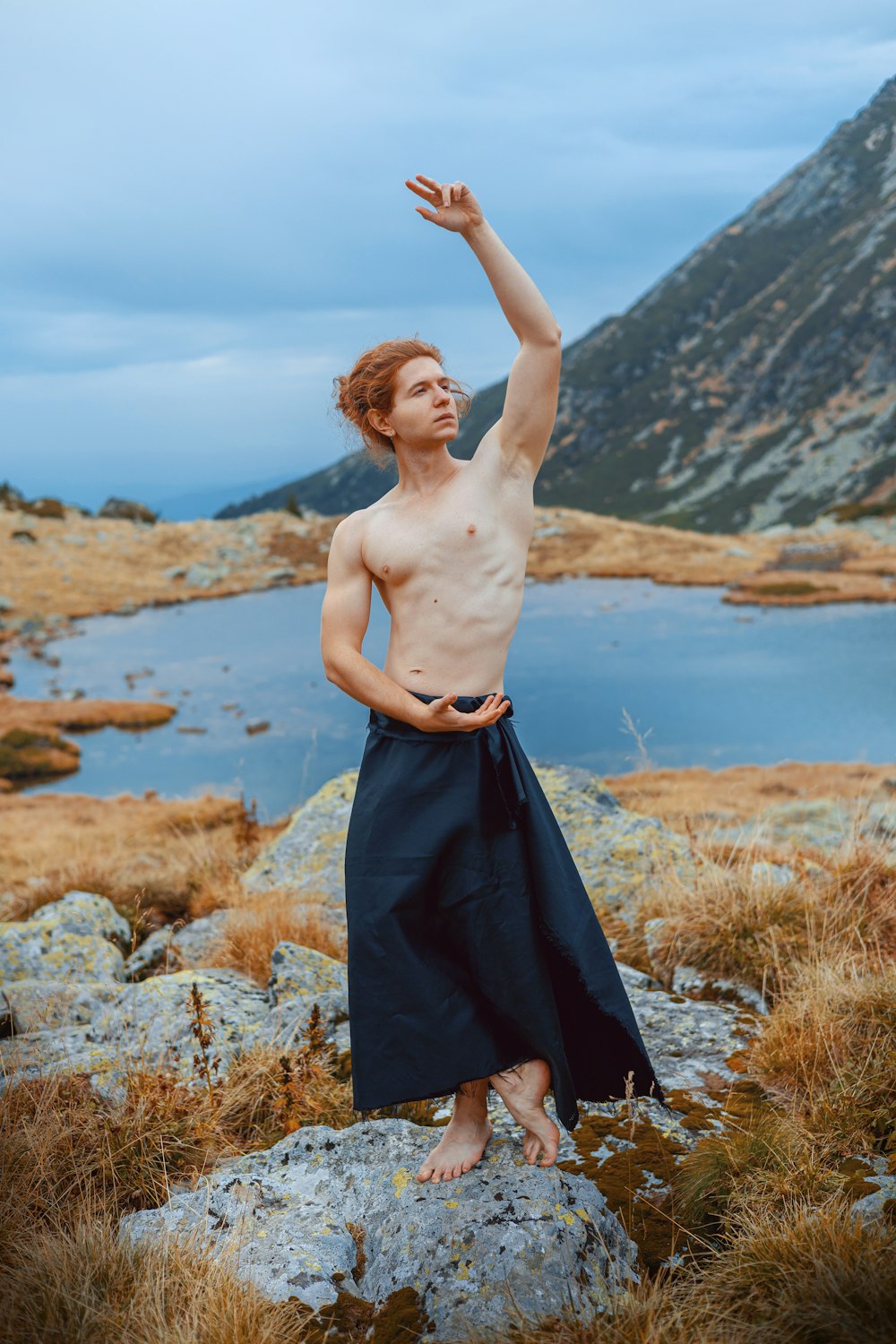a shirtless man standing on top of a rock
