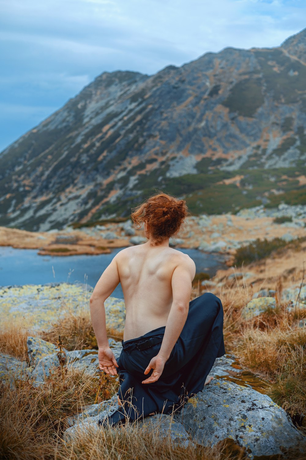 a shirtless man sitting on top of a rock