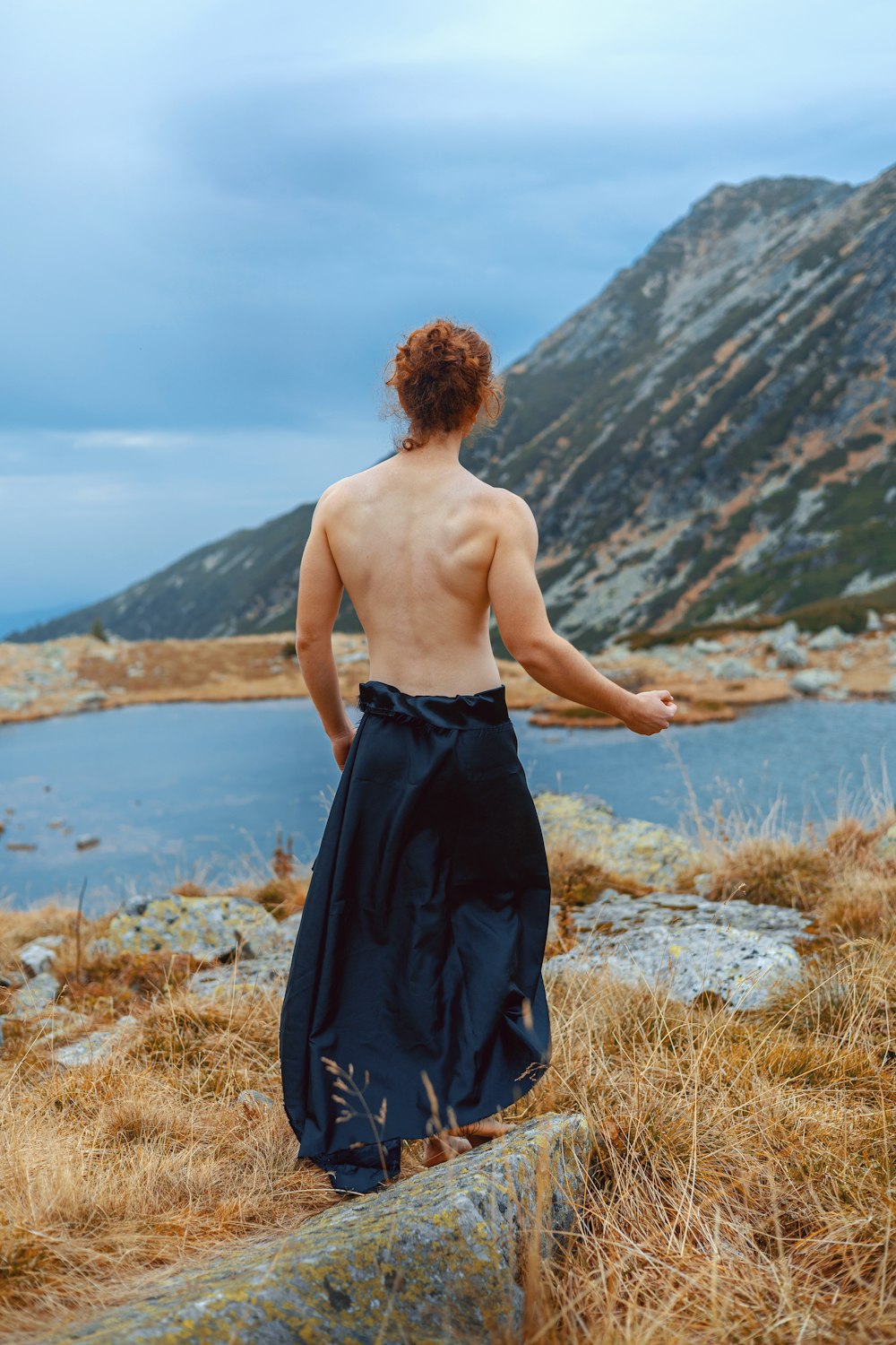 a man standing on top of a hill next to a body of water