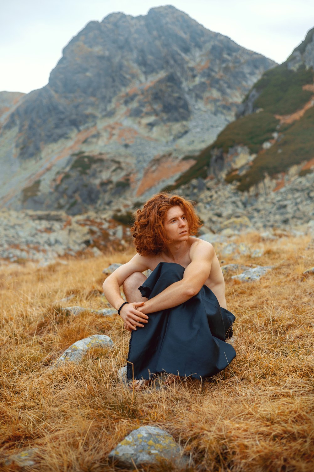 a woman in a blue dress sitting on a hill