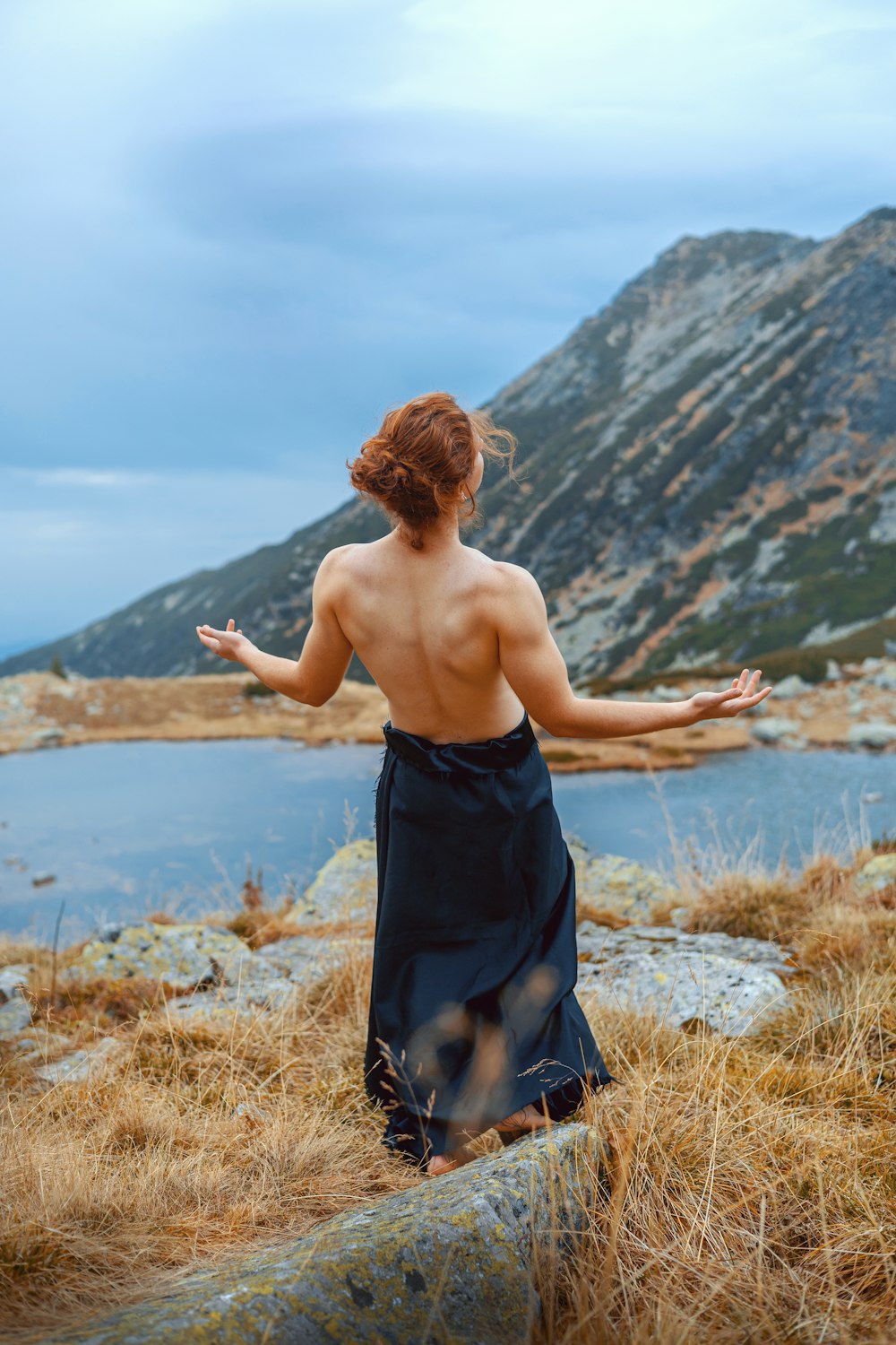 a woman in a black dress standing on a hill