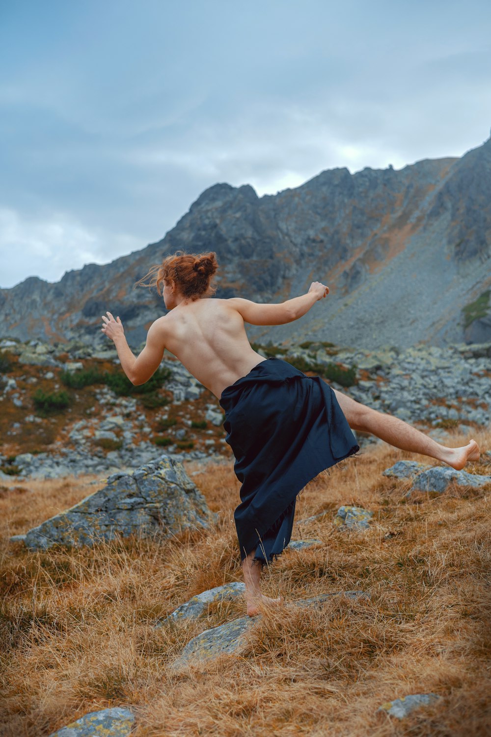 a shirtless man in a blue skirt kicking a frisbee