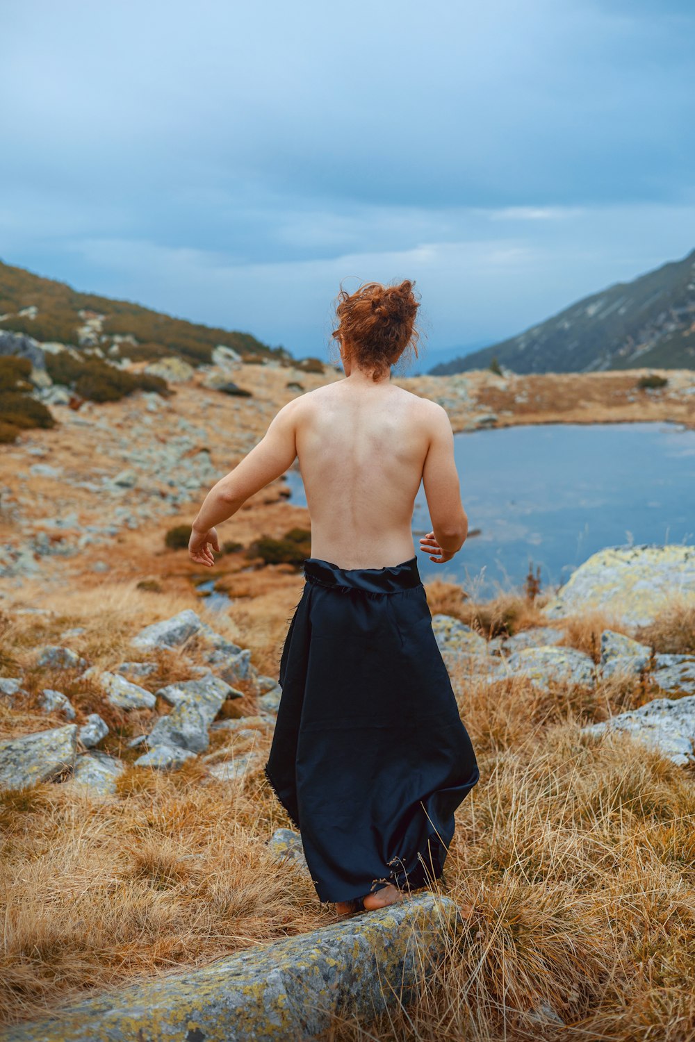 a man with no shirt on walking up a hill