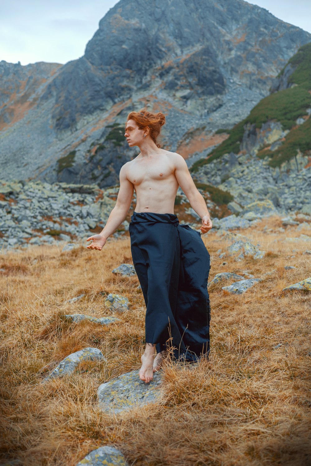 a shirtless man standing on a rocky hillside