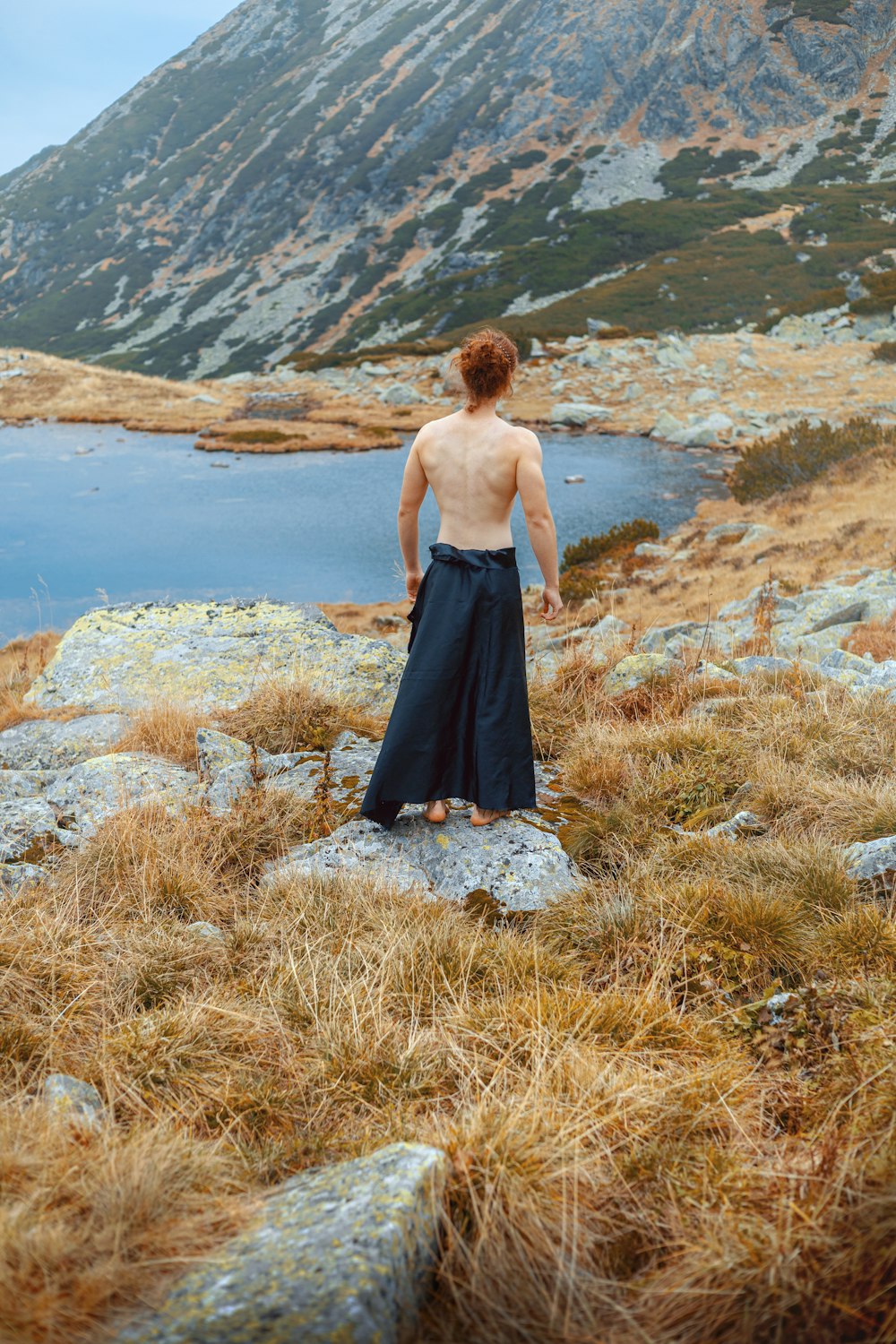 a man standing on top of a grass covered hillside