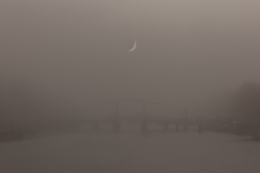 a foggy river with a bridge in the distance