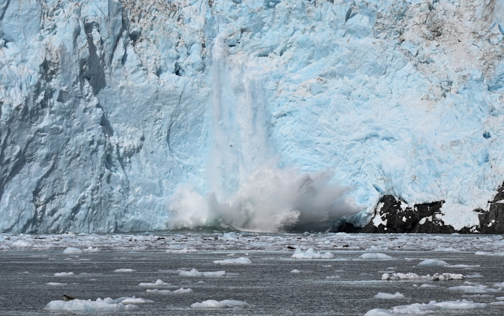 a large glacier wall with a large wave coming out of it