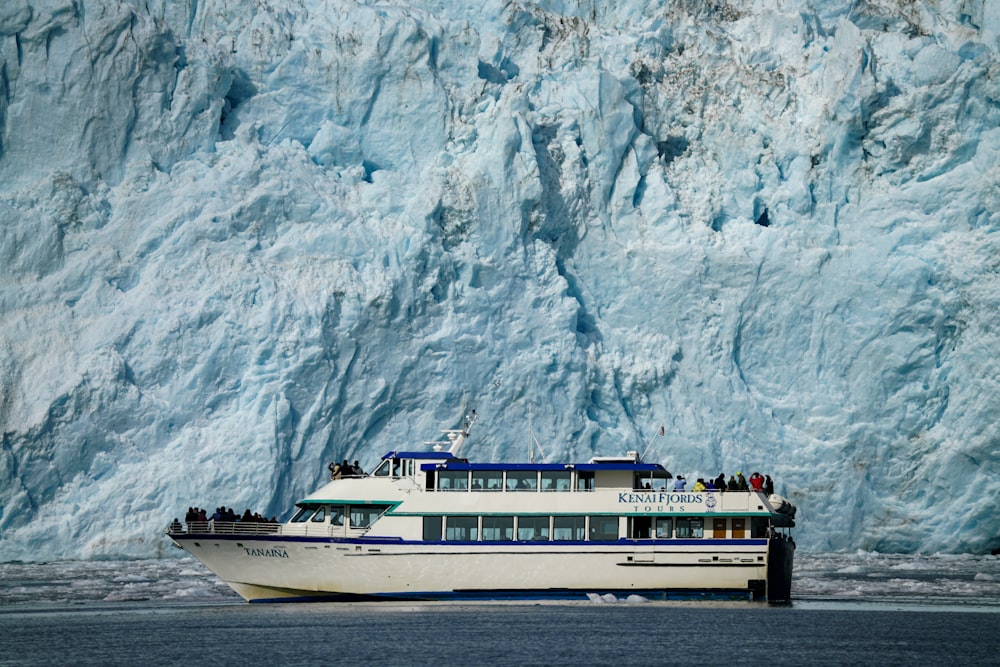 a boat in front of a large glacier wall