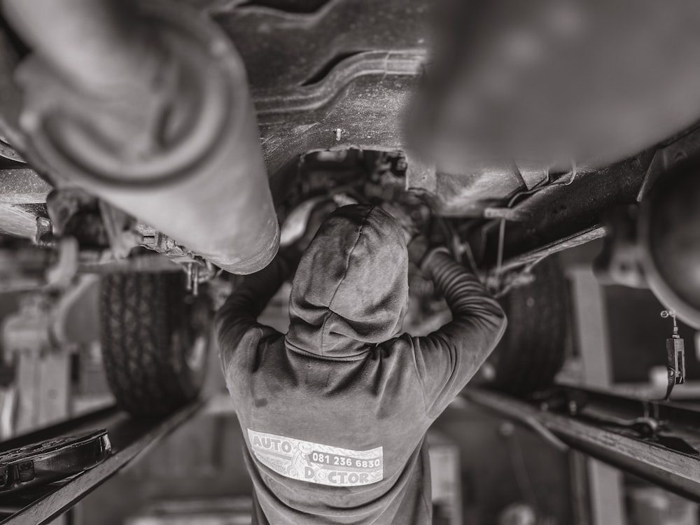 a black and white photo of a man working on a vehicle