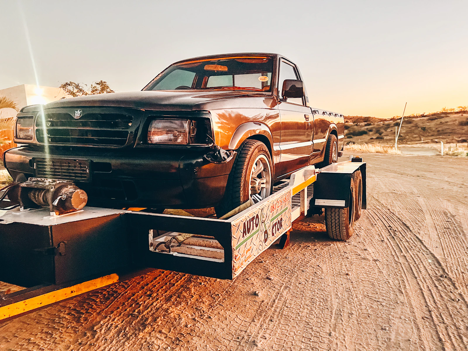 Truck and flatbed trailer on the road at sunset