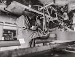 A mechanic working under the hood of a modern car in a clean workshop.