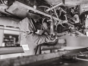 Mechanic working under the hood of a car with tools