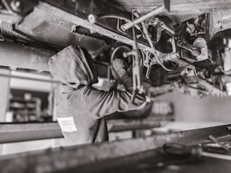 Mobile mechanic working under the hood of a car with tools laid out on a matte black mat.