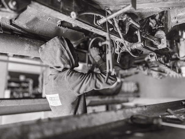 A mechanic working under the hood of a car in a clean garage.