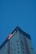 A tall, modern skyscraper with a glass facade dominates the scene, reflecting the clear blue sky. The building features the logo and name of a well-known hotel chain near the top, highlighting its corporate identity.