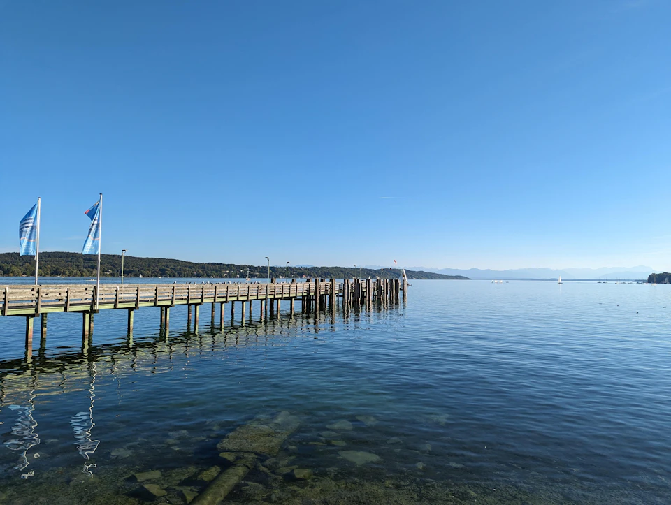 Two wooden piers extend into calm water with blue flags fluttering in the breeze