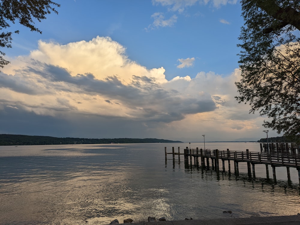 a wooden dock sitting on top of a lake under a cloudy sky