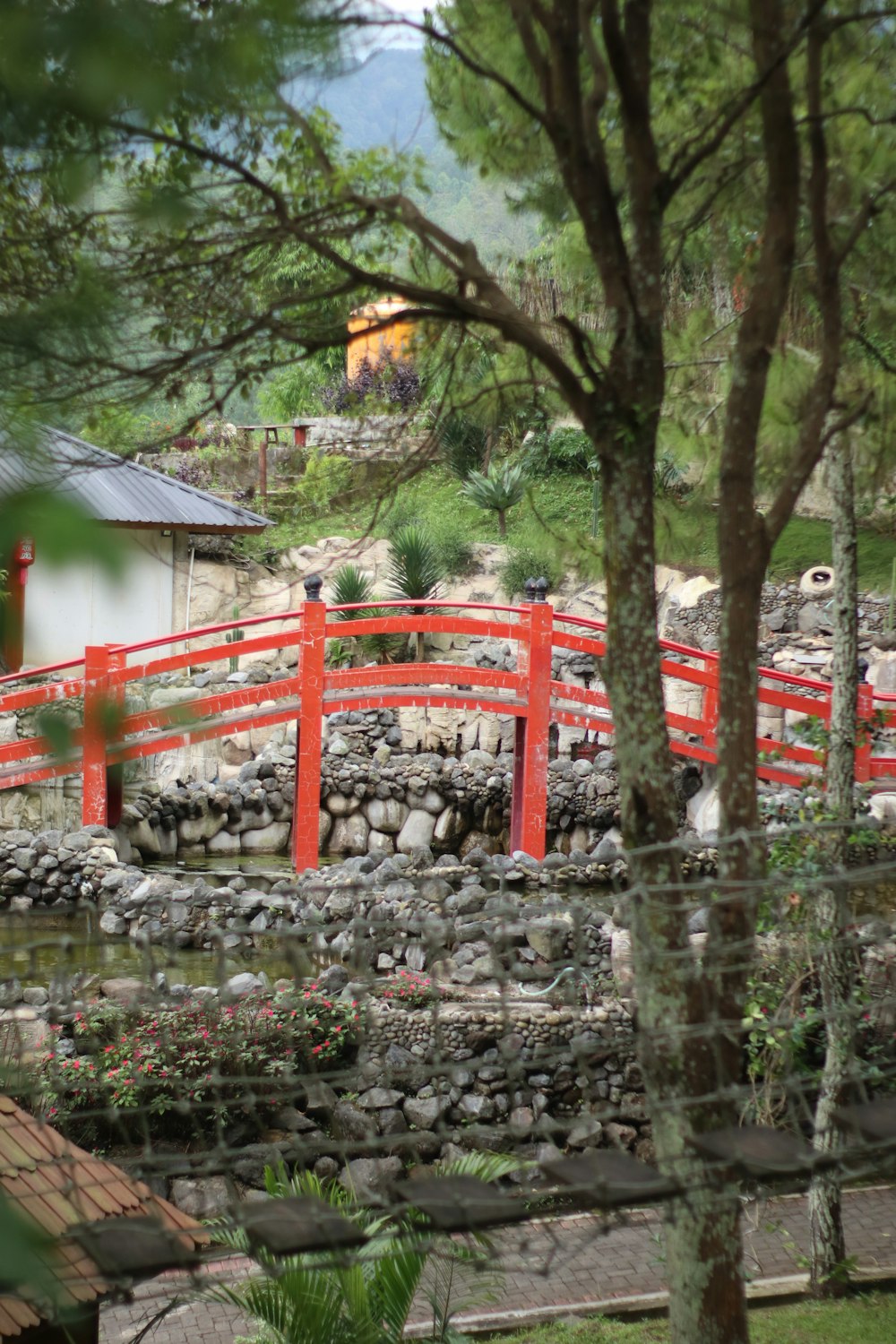 a red bridge over a small pond in a park