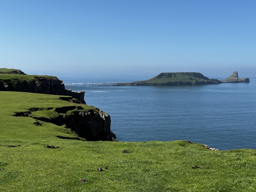 a large body of water sitting next to a lush green hillside