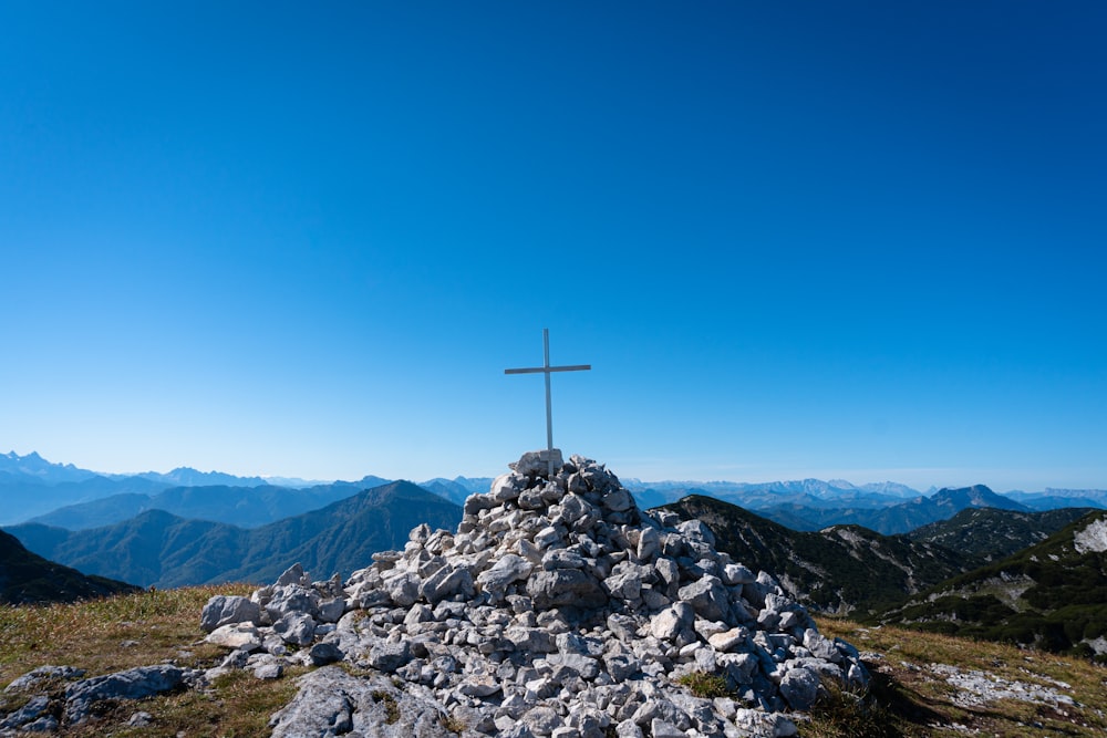 a cross on top of a mountain with mountains in the background