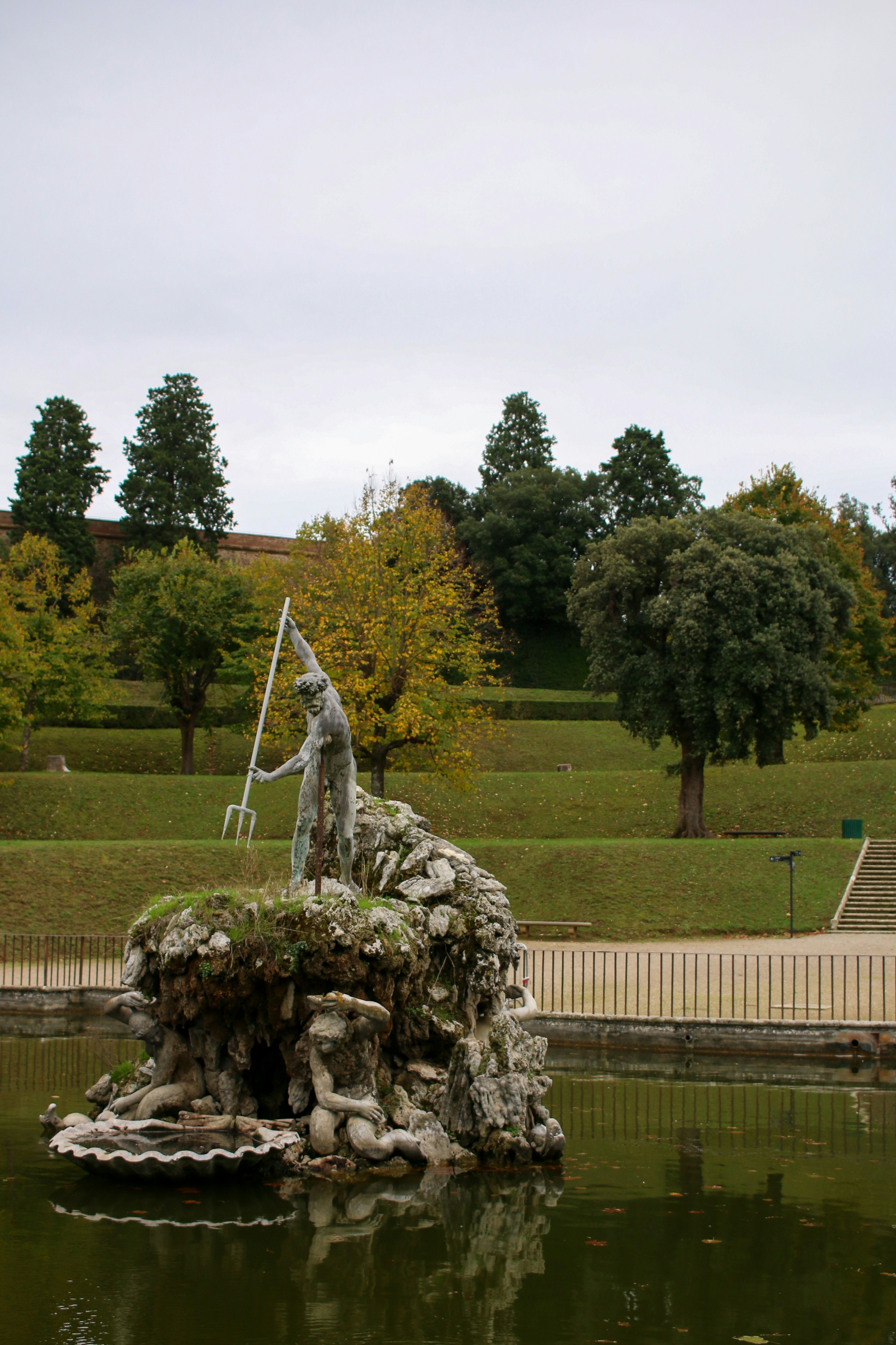 a statue of a man on a rock in a pond