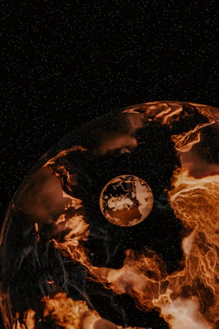 A planet-like sphere dominates the foreground, appearing to be engulfed in fiery, molten lava-like textures. Beyond, a smaller celestial body hovers in space, surrounded by a dark starry sky. The overall scene gives an impression of cosmic intensity and otherworldly beauty.