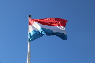 a red, white and blue flag flying in the wind