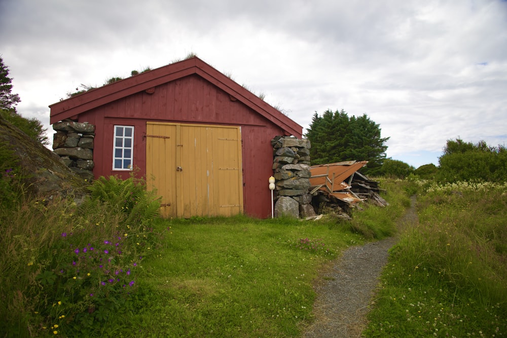 a small red building sitting on top of a lush green field