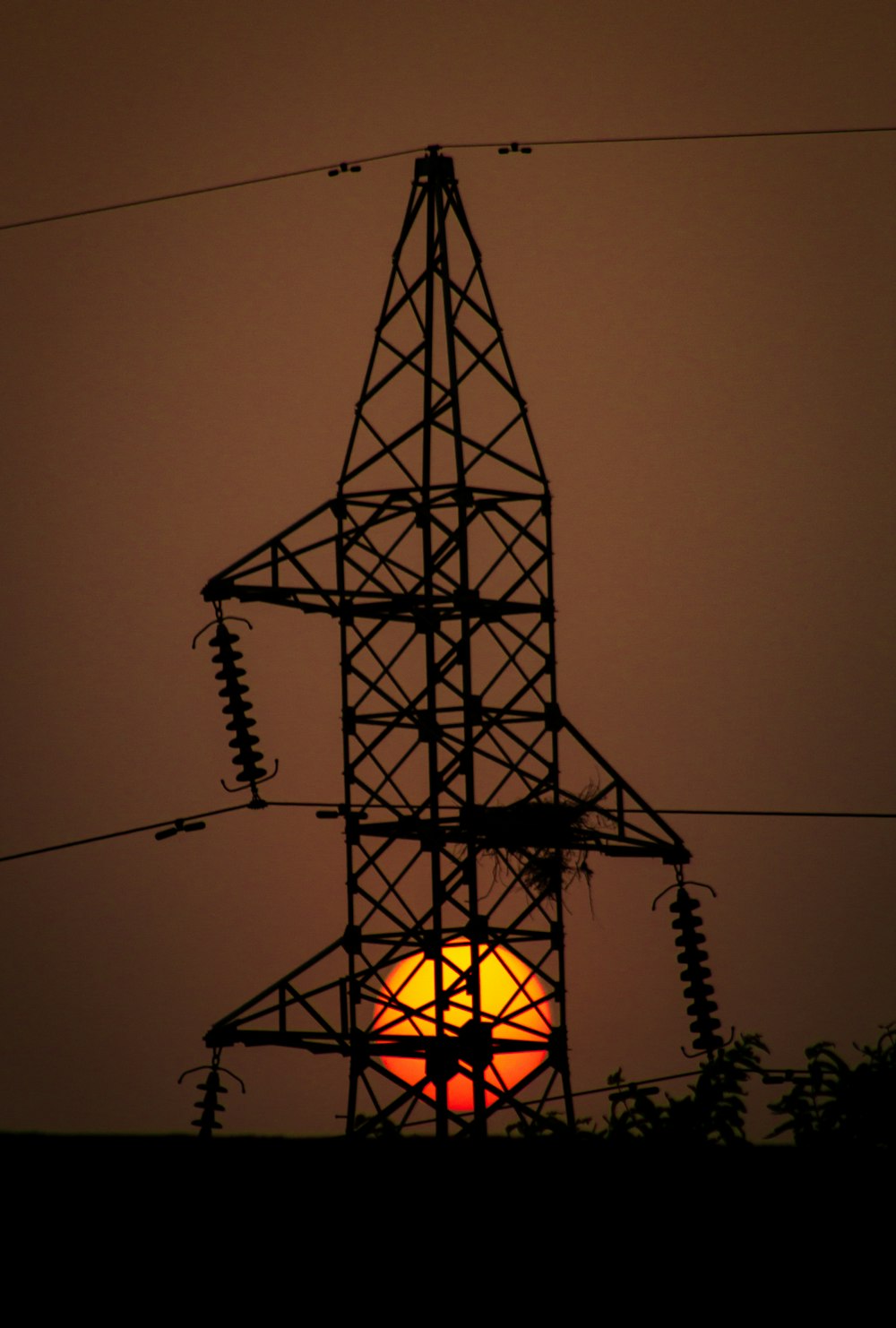 the sun is setting behind a power line tower