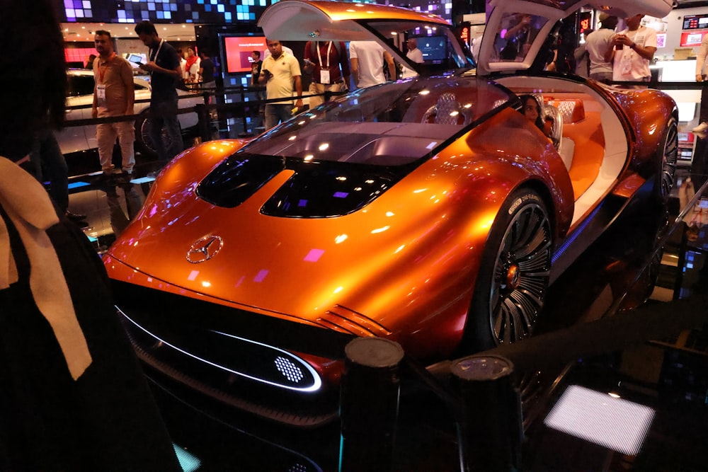 Une voiture de sport orange exposée dans un salon de l’auto