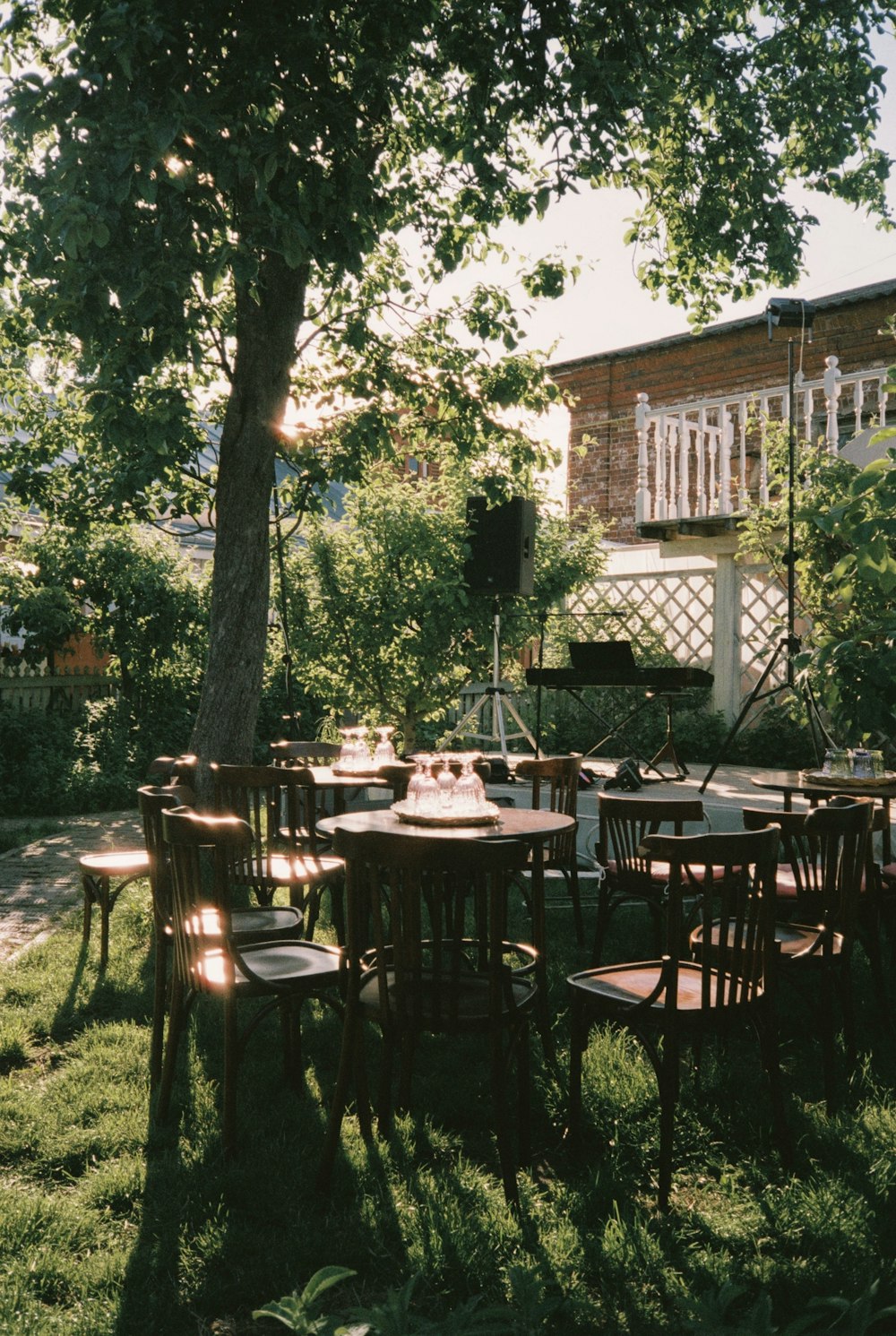 a group of wooden tables and chairs under a tree